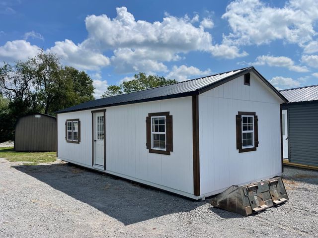 White cabin with brown trim and shutters